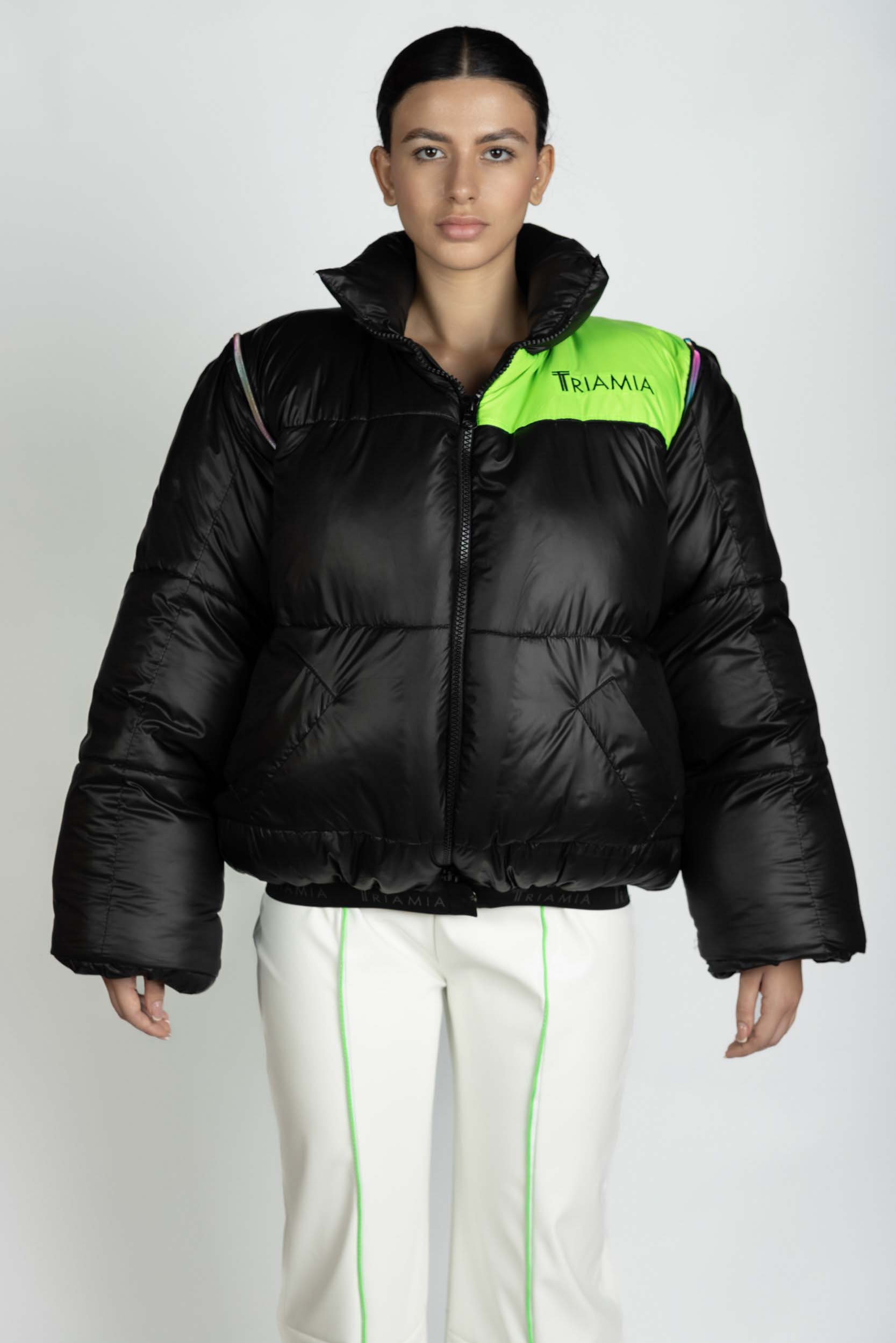 Oversized black and neon green puffer jacket with zipper and Triamia logo on one side. It also has detachable sleeves in order to transform it in a vest.